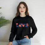 Person wearing a black sweatshirt with 'LOVE' and heart designs, sitting on a white surface with a plant in the background.