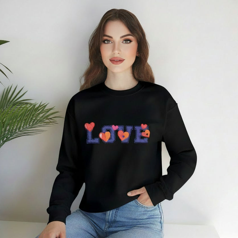 Person wearing a black sweatshirt with 'LOVE' and heart designs, sitting on a white surface with a plant in the background.