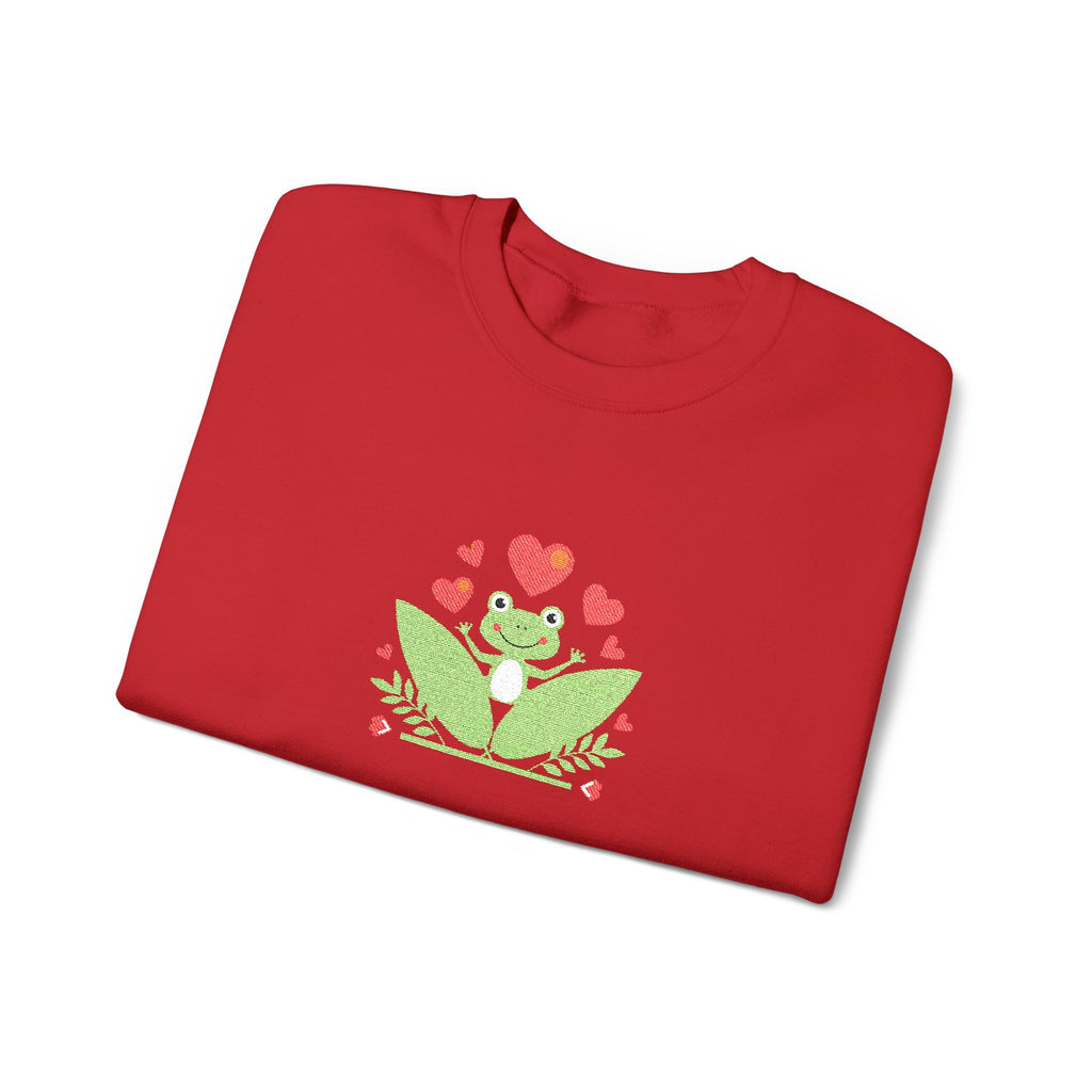 Folded red shirt with a green frog and heart design on a white background