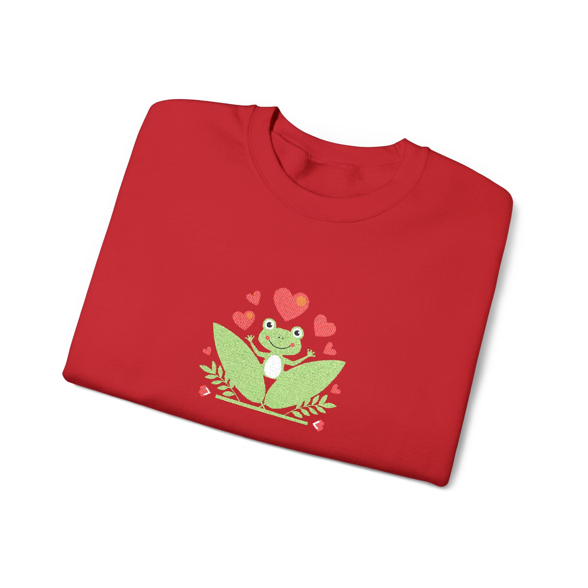 Folded red shirt with a green frog and heart design on a white background