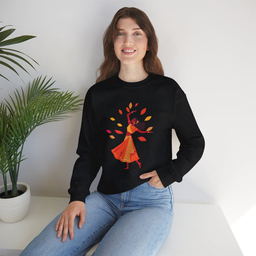 Person wearing a black sweatshirt with a colorful design, sitting in a room with a plant.