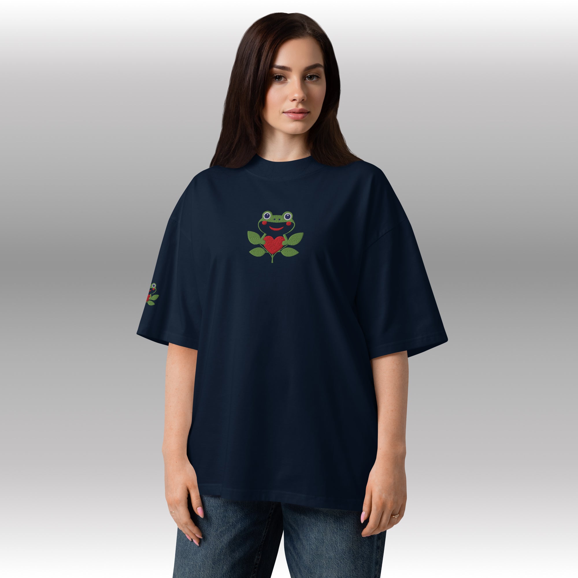 Person wearing a navy blue t-shirt with a frog design on a plain background