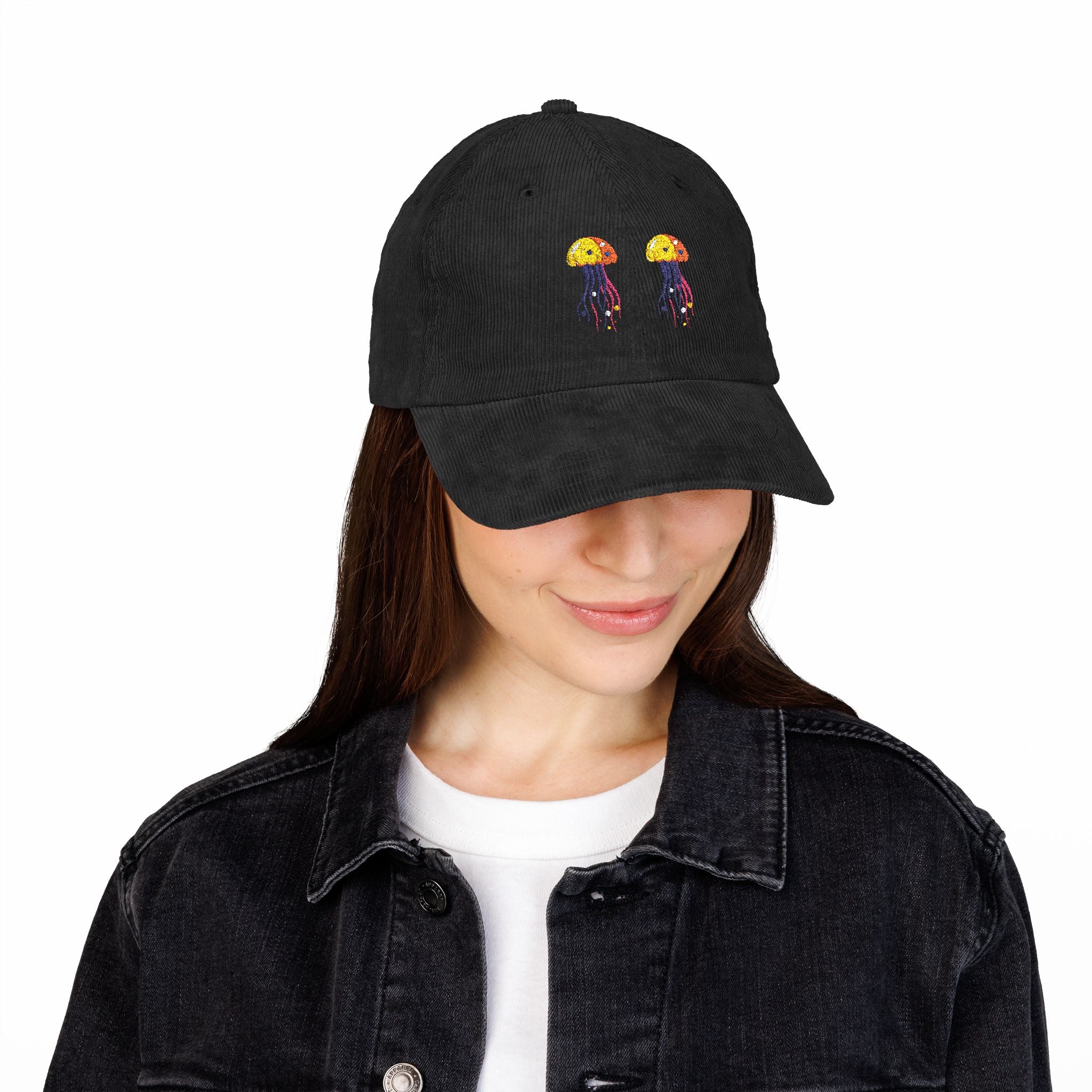Black cap with embroidered design worn by a person on a white background