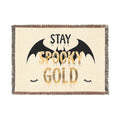 Blanket with 'Stay Spooky Gold' text and bat designs on a beige background