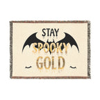 Blanket with 'Stay Spooky Gold' text and bat designs on a beige background