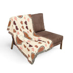 Brown and beige patterned blanket draped over a brown chair on a white background