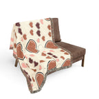 Brown and pink patterned blanket draped over a brown chair on a white background