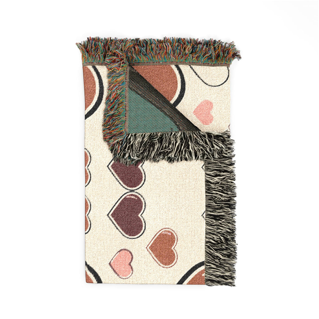 Decorative throw blanket with heart pattern and fringed edge on a white background