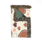 Decorative throw blanket with heart patterns and fringe on a white background