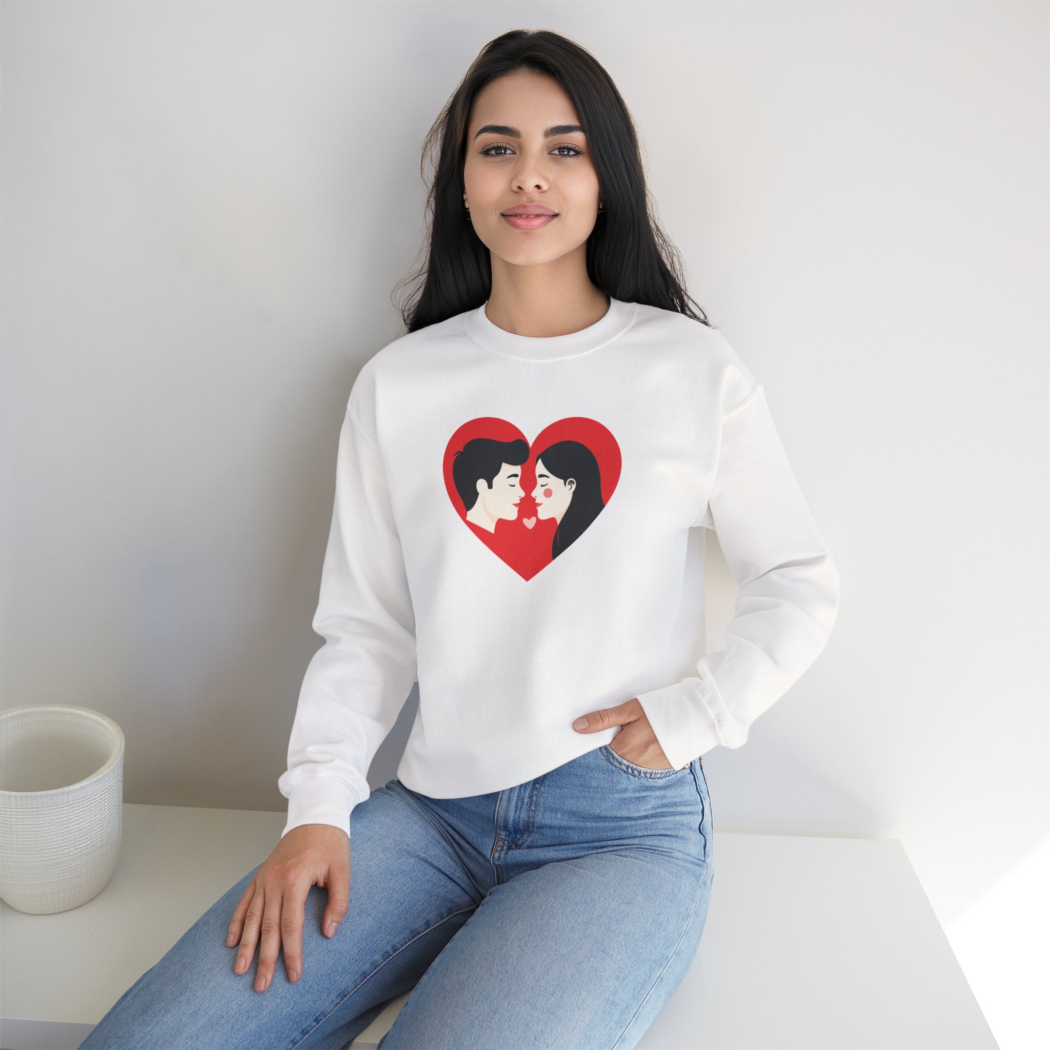 Woman wearing a white sweatshirt with a heart design sitting on a white surface.