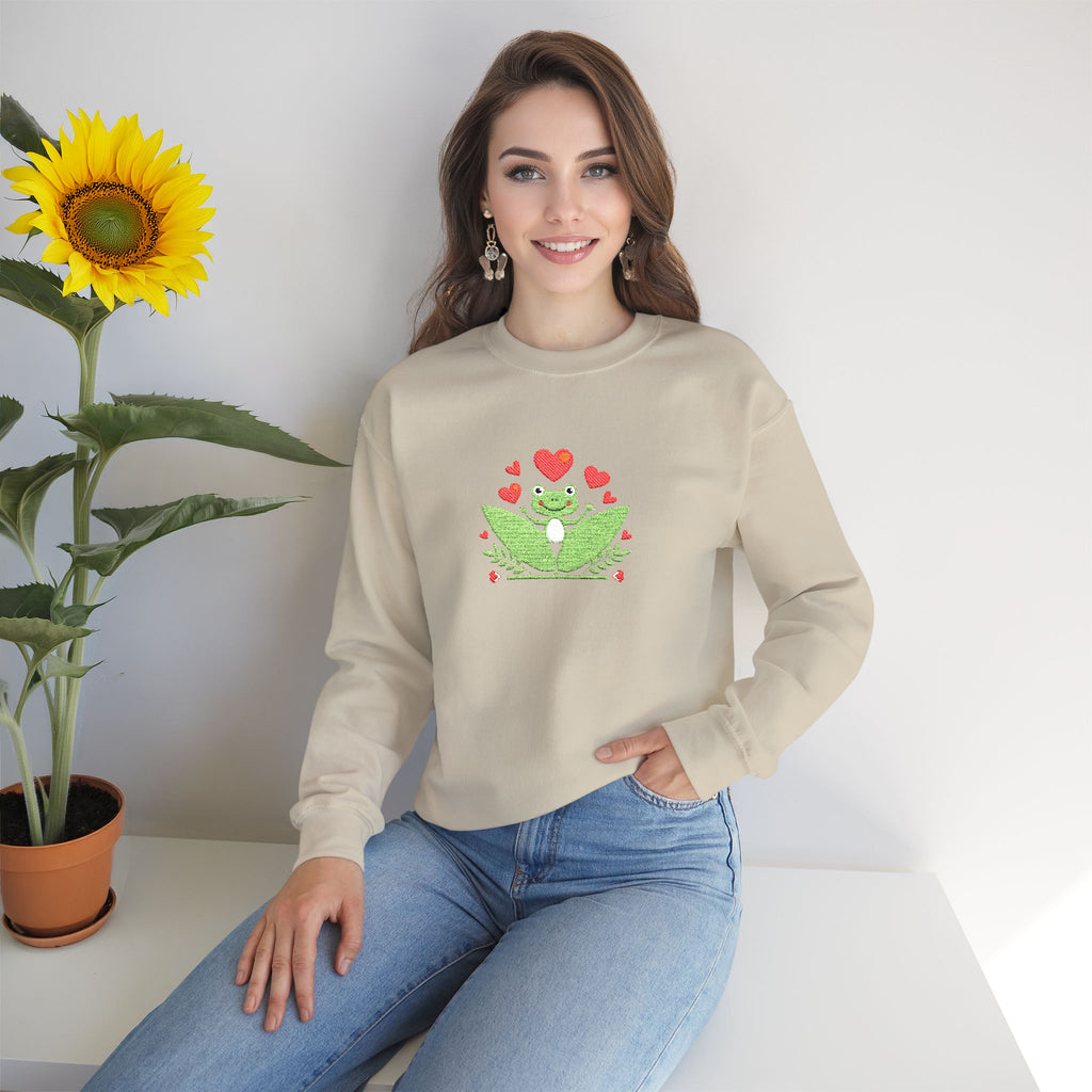 Woman wearing a beige sweatshirt with a graphic design, sitting next to a sunflower.