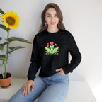 Woman wearing a black sweatshirt with a frog graphic sitting next to a sunflower.