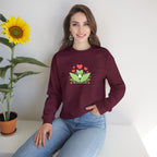 Woman wearing a maroon sweatshirt with a frog design, sitting next to a sunflower.