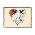 Blanket with a design of a woman's face and birds, framed by a heart, on a white background.