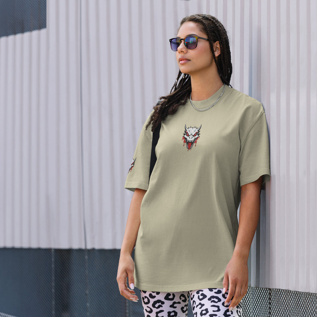 Woman wearing a light green t-shirt with a graphic design, standing against a textured wall.