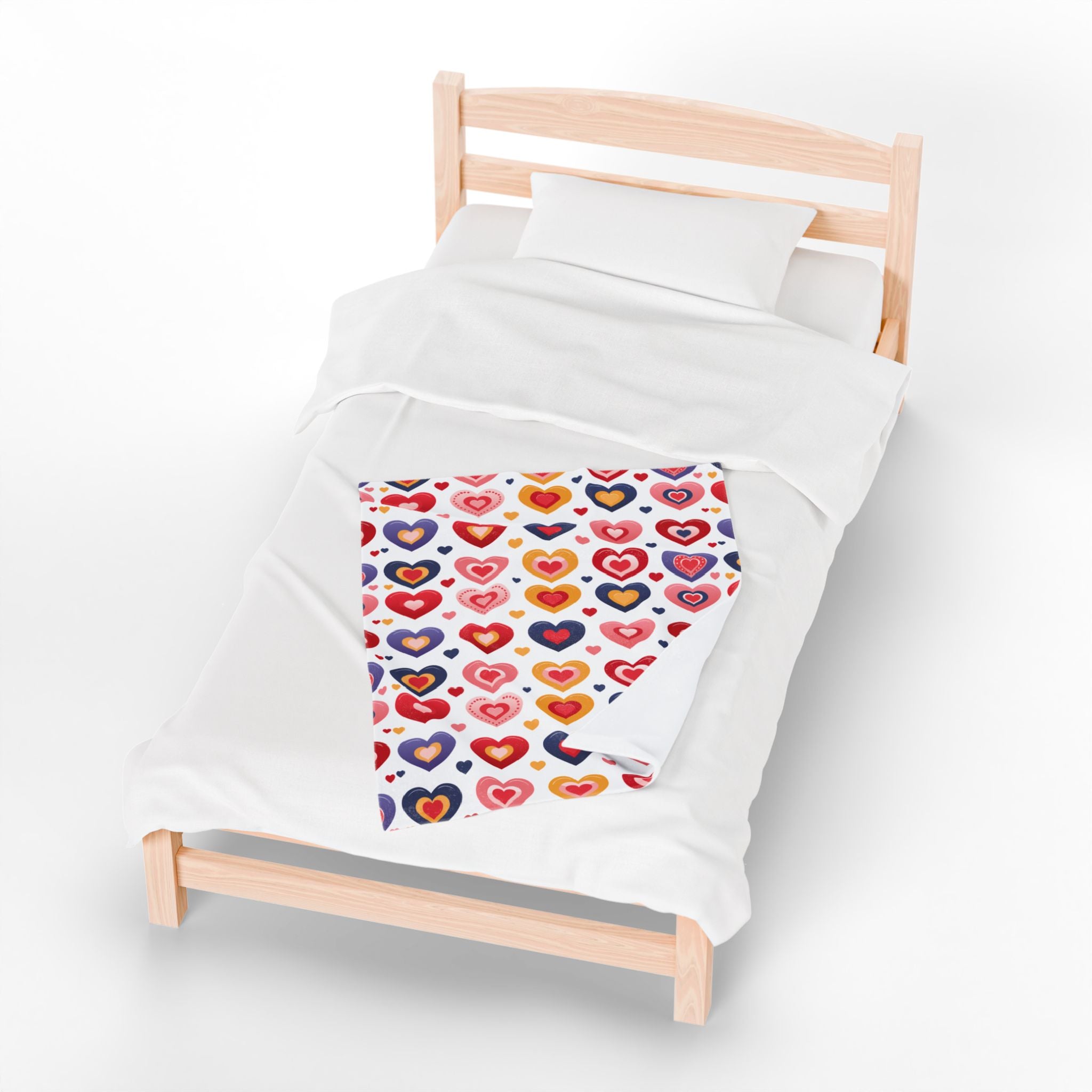 Children's bed with a colorful heart-patterned duvet cover on a white background
