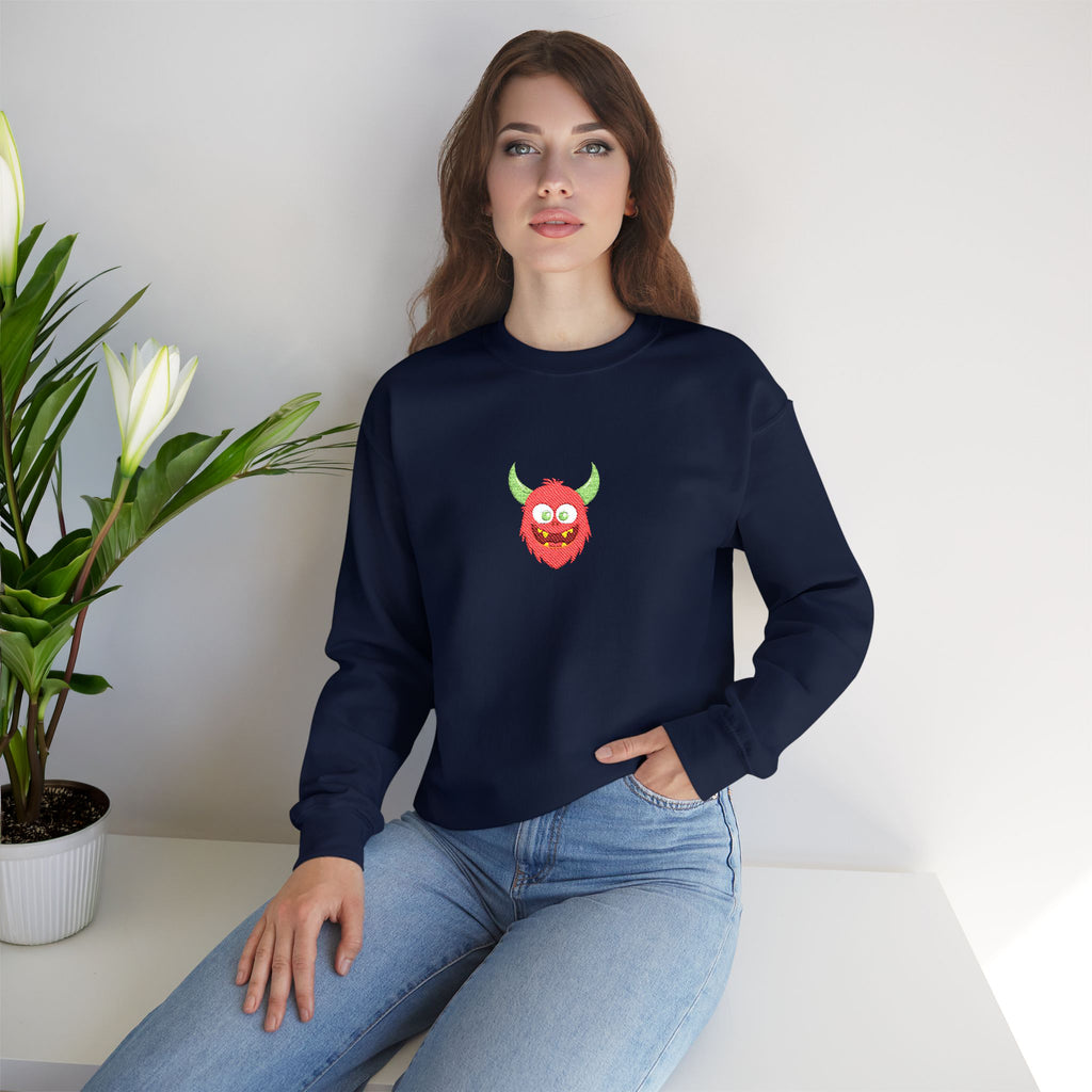 Woman wearing a navy blue sweatshirt with a colorful graphic design, sitting on a white surface with a plant in the background.