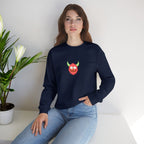 Woman wearing a navy blue sweatshirt with a colorful graphic design, sitting on a white surface with a plant in the background.