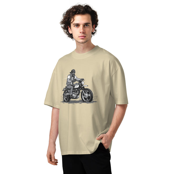 Man wearing a beige t-shirt with a graphic of a person on a motorcycle.