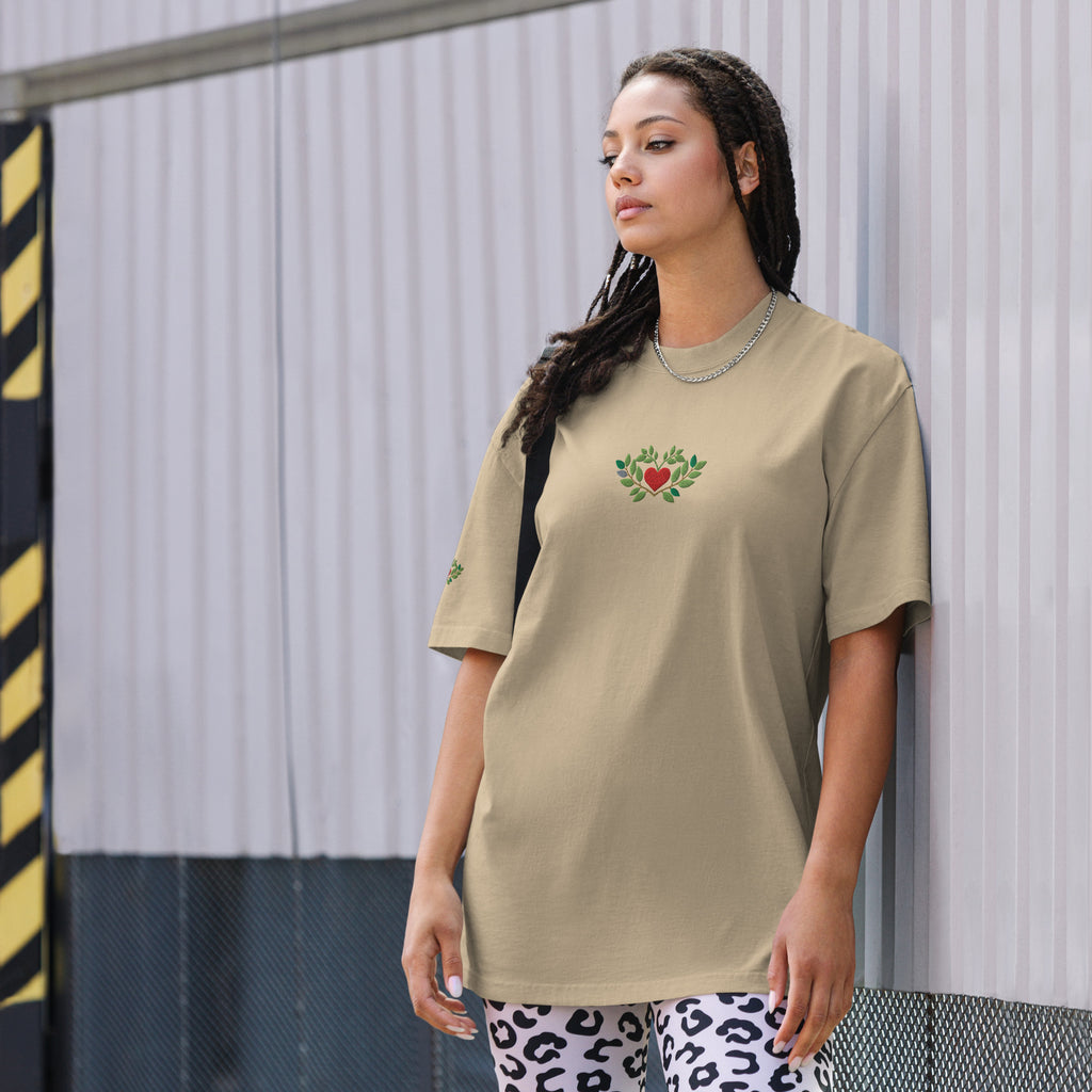 Woman wearing a beige t-shirt with a heart design against a metallic wall.