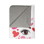Folded blanket with gray hood and eye design featuring heart shapes on a white background