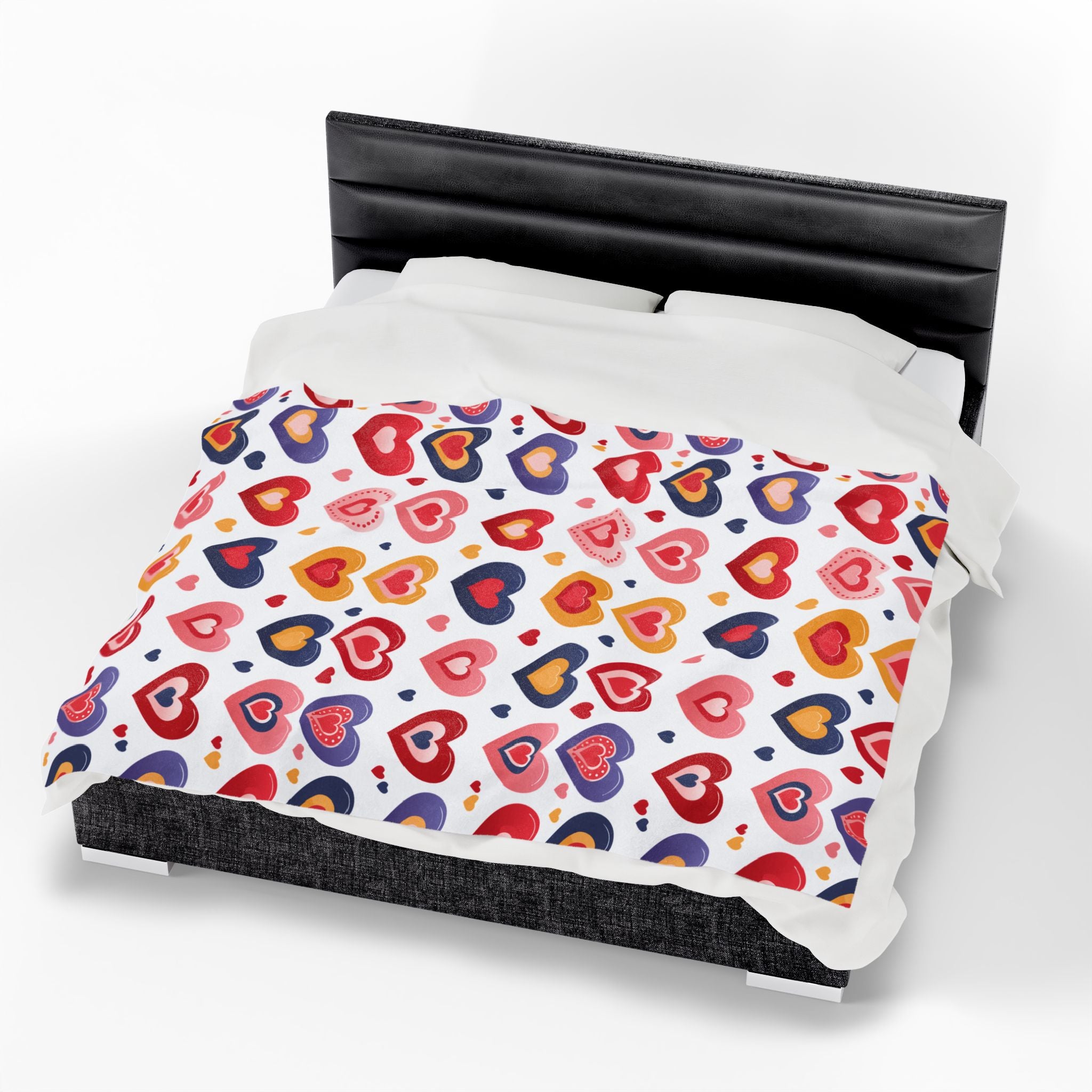 Colorful heart-patterned comforter on a bed with a white background