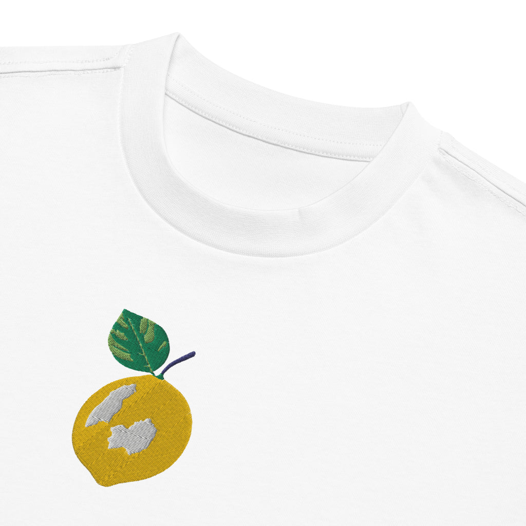 Embroidered lemon design on a white shirt with green leaves.