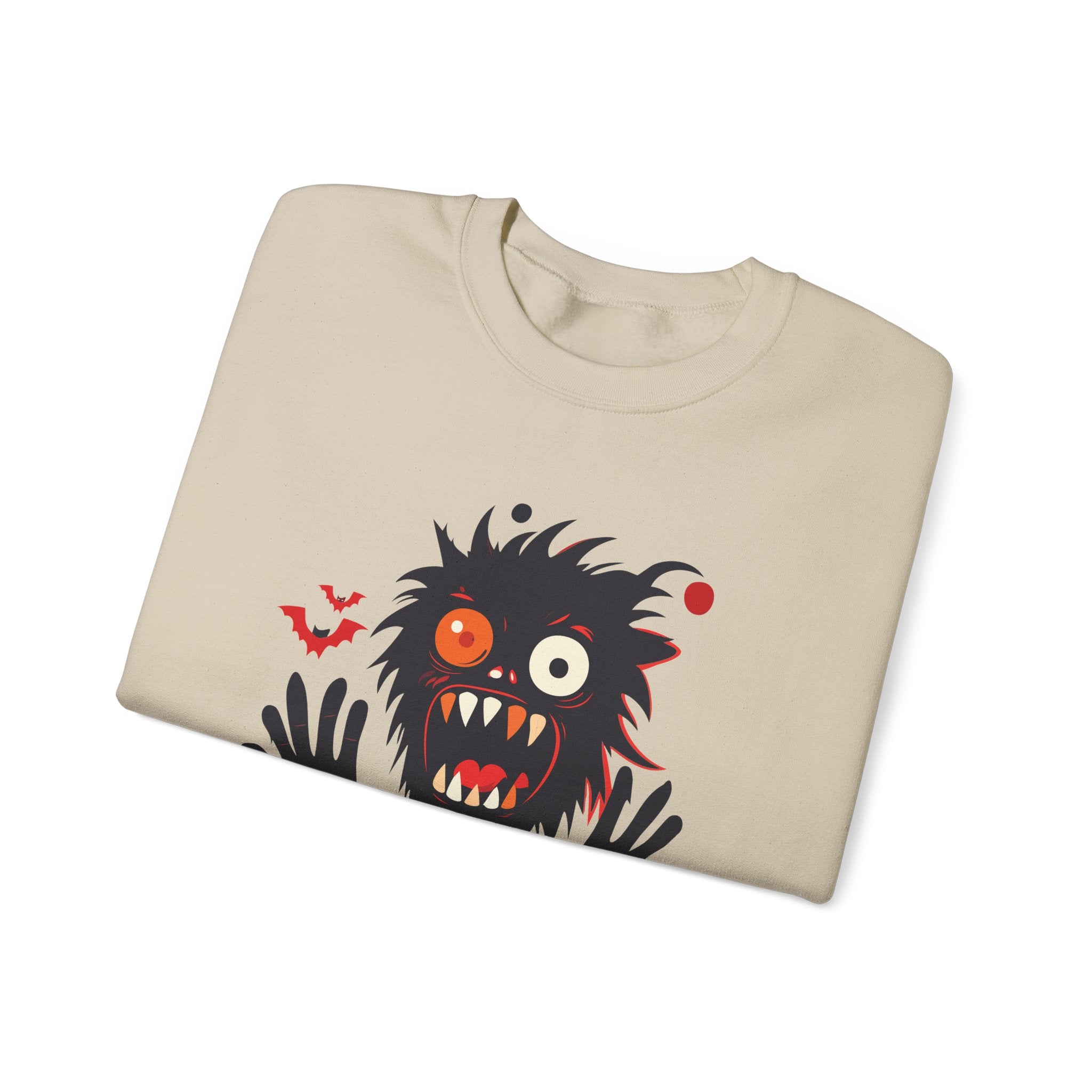Folded beige sweatshirt with a cartoon monster design on a white background