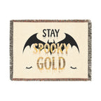 Blanket with 'Stay Spooky Gold' text and bat designs on a beige background