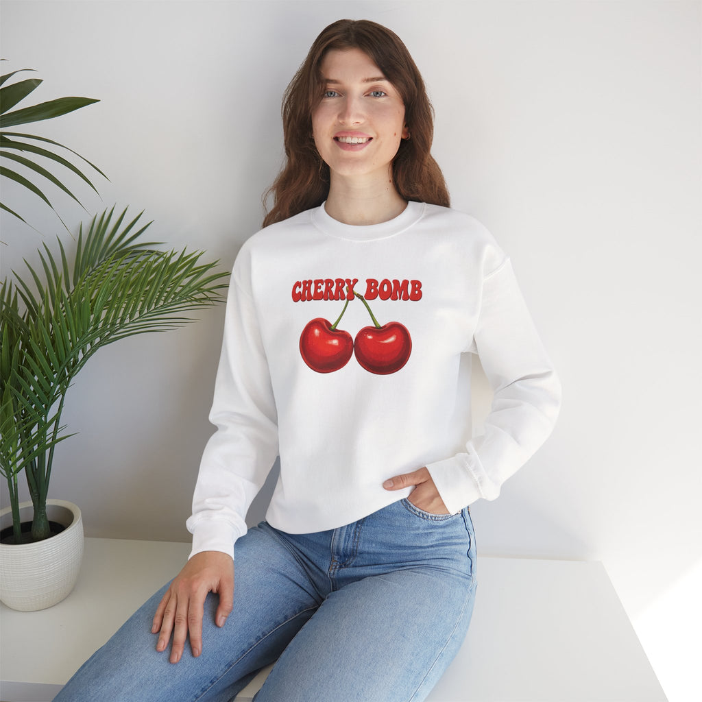 Woman wearing a white sweatshirt with 'Cherry Bomb' design sitting on a white couch.