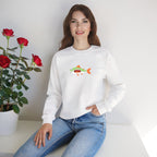 Woman wearing a white sweatshirt with a colorful fish design, sitting next to a potted plant with red flowers.
