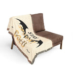 Brown chair with a decorative blanket featuring bat designs and text on a white background
