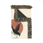 Woven blanket with bird design and fringed edges on a white background