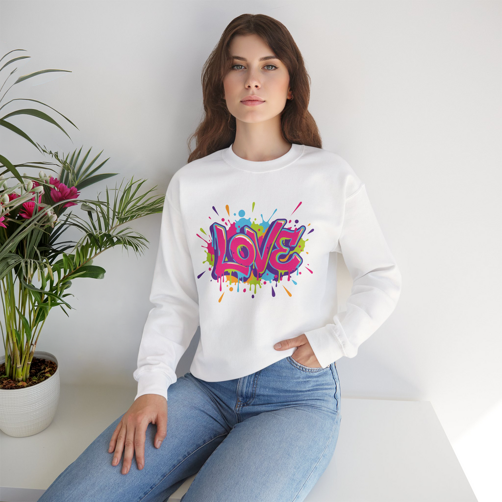 Woman wearing a white sweatshirt with a colorful 'LOVE' design, sitting in a room with a plant.