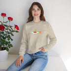 Woman wearing a beige sweatshirt with a fish graphic, sitting on a white surface with red roses and a plant in the background.